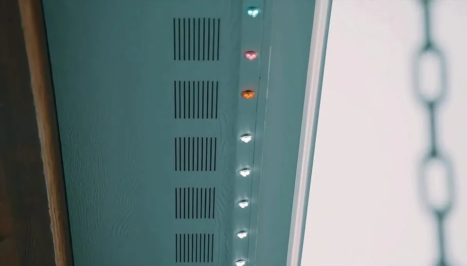 Close up of an aluminum lighting track with a row of LED nodes mounted inside the channel along a roof edge.
